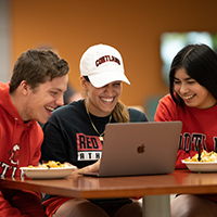 Students working together on a computer in Cortland gear